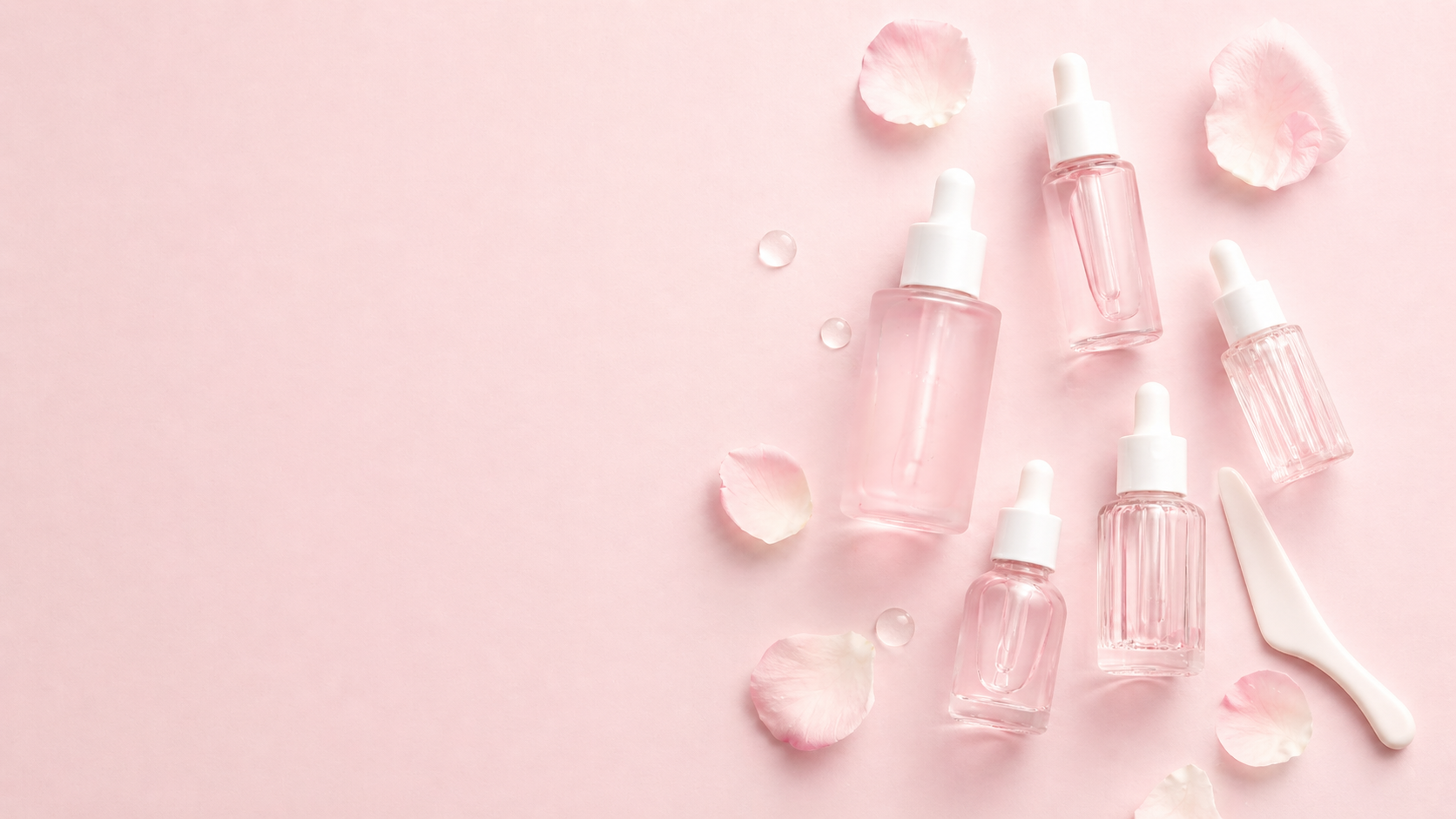 Flat lay sérums roses fond rose pétales — ambiance K-Beauty header collection