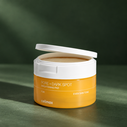 Pot celimax Pore+ Dark Spot Brightening Pad présenté sur un décor vert lumineux