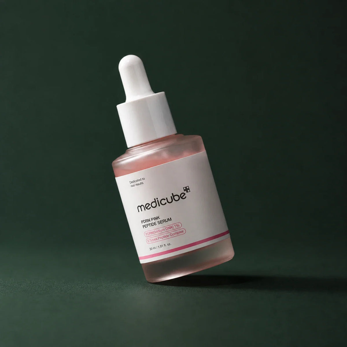 Medicube Ampoule PDRN Rose et Peptides, flacon incliné sur fond vert profond