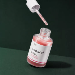 Medicube Ampoule PDRN Rose et Peptides avec pipette sur fond vert profond