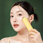 Appareil AGE-R Booster Pro Lemon Medicube utilisé sur la joue sur fond vert profond