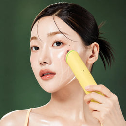 Appareil AGE-R Booster Pro Lemon Medicube utilisé sur la joue sur fond vert profond