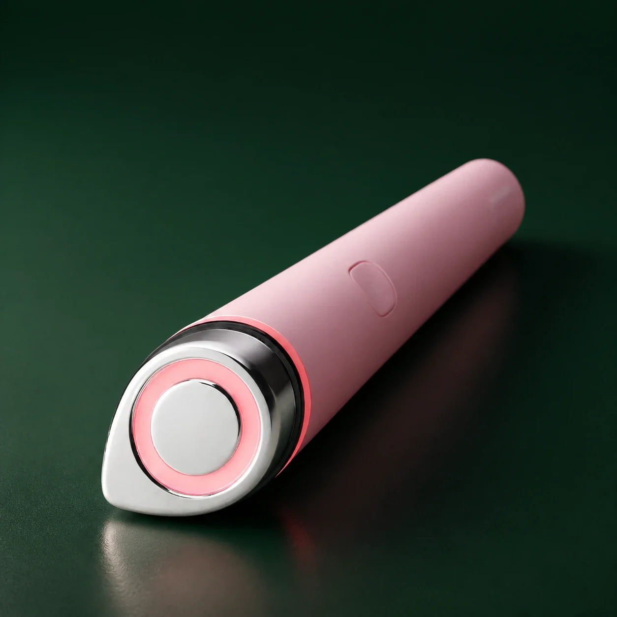 Appareil AGE-R Booster Pro Mini Rose Medicube allumé sur fond vert profond