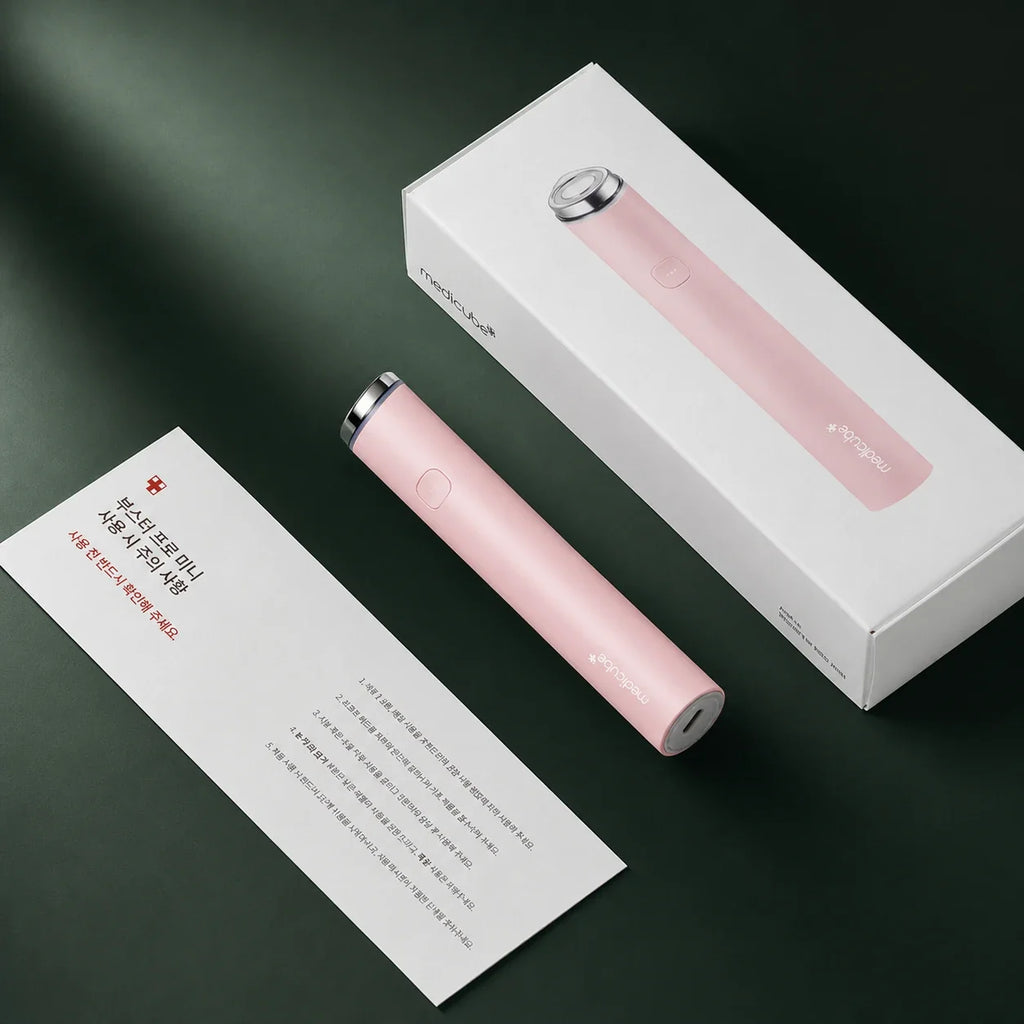 Appareil AGE-R Booster Pro Mini Rose Medicube avec coffret et notice sur fond vert profond