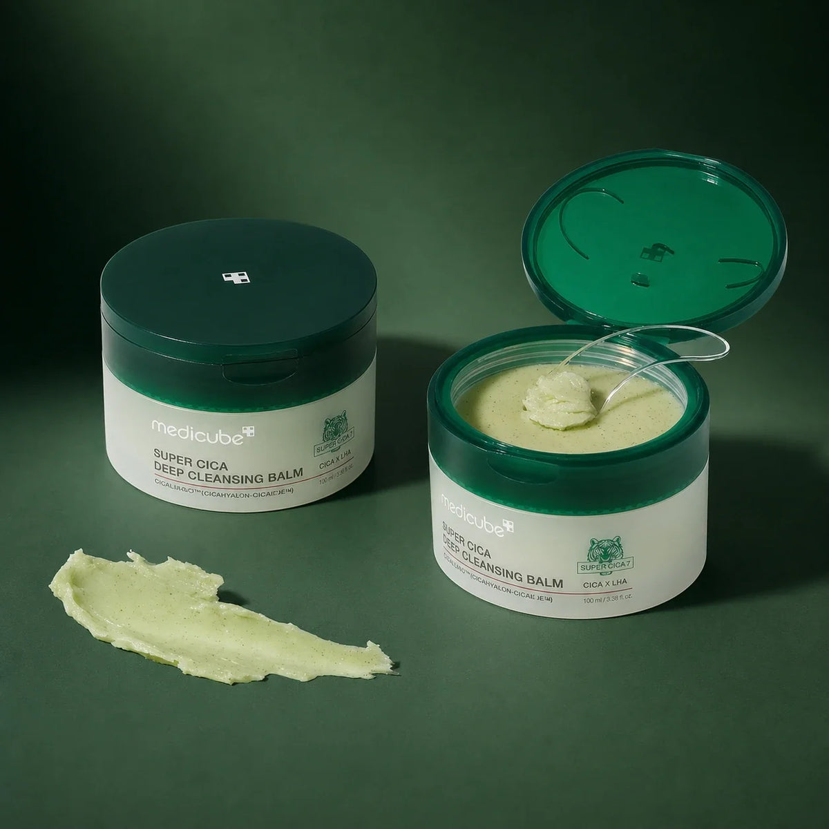 Baume Démaquillant Super Cica Medicube ouvert avec spatule sur fond vert profond