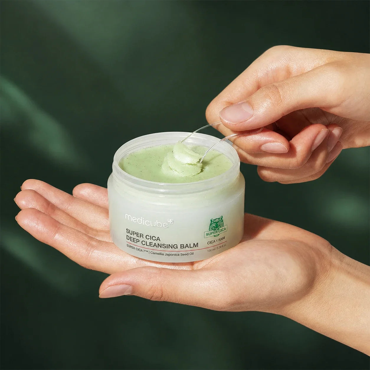 Baume Démaquillant Super Cica Medicube prélevé à la spatule sur fond vert profond