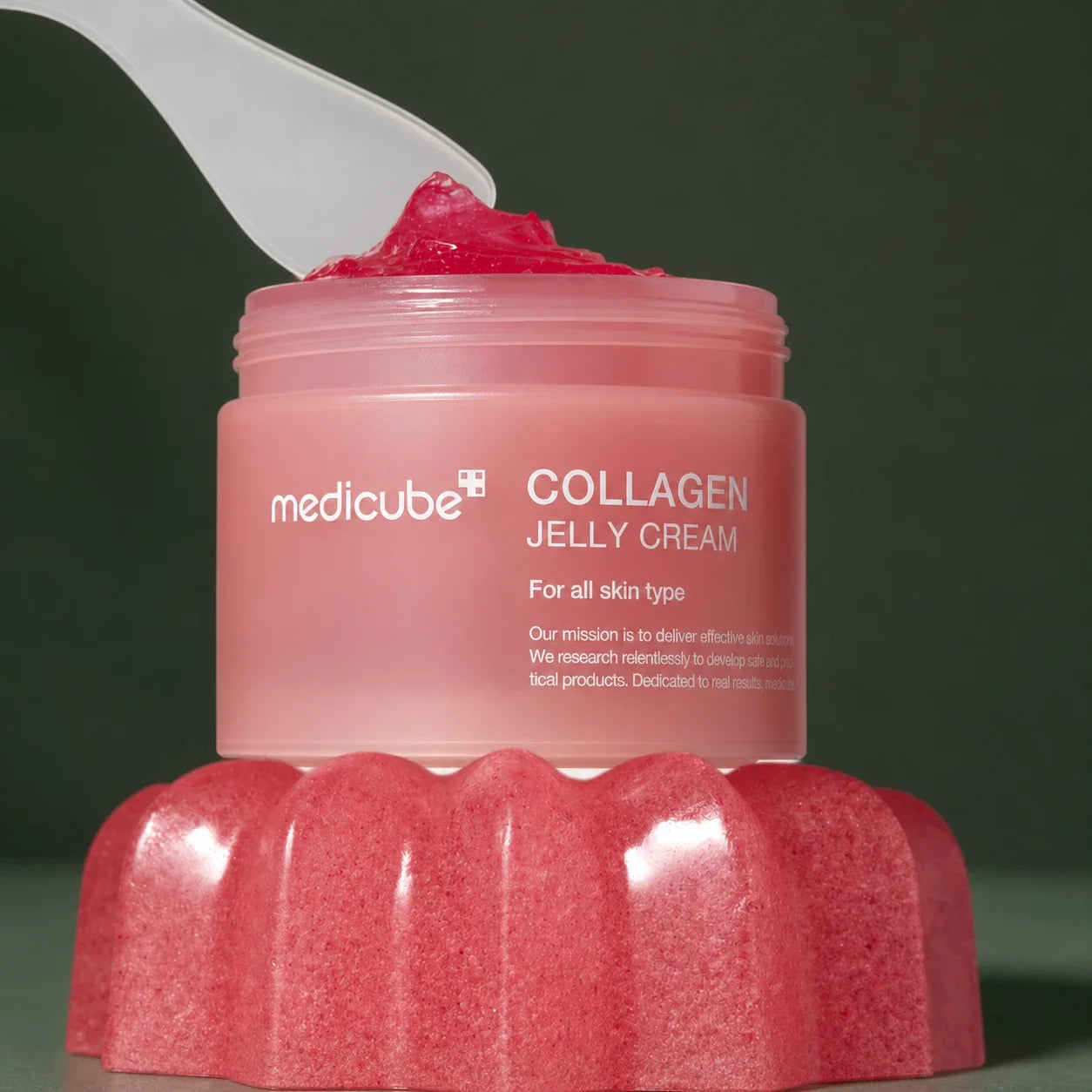 Medicube Crème Gelée au Collagène – pot ouvert et spatule sur fond vert premium