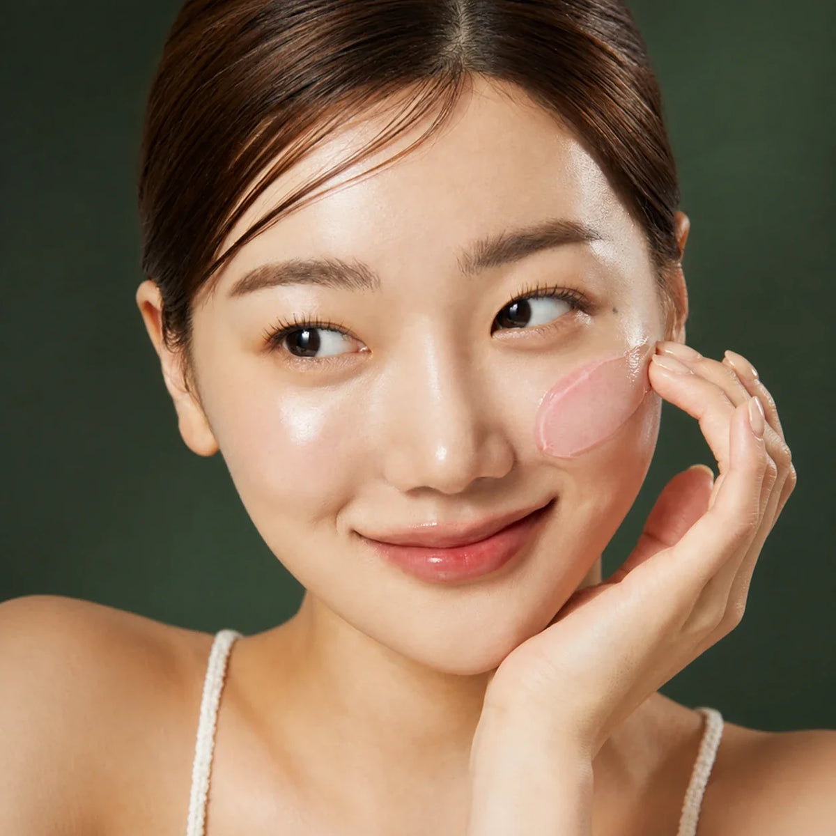 Medicube Crème Gelée au Collagène – application sur la joue sur fond vert premium