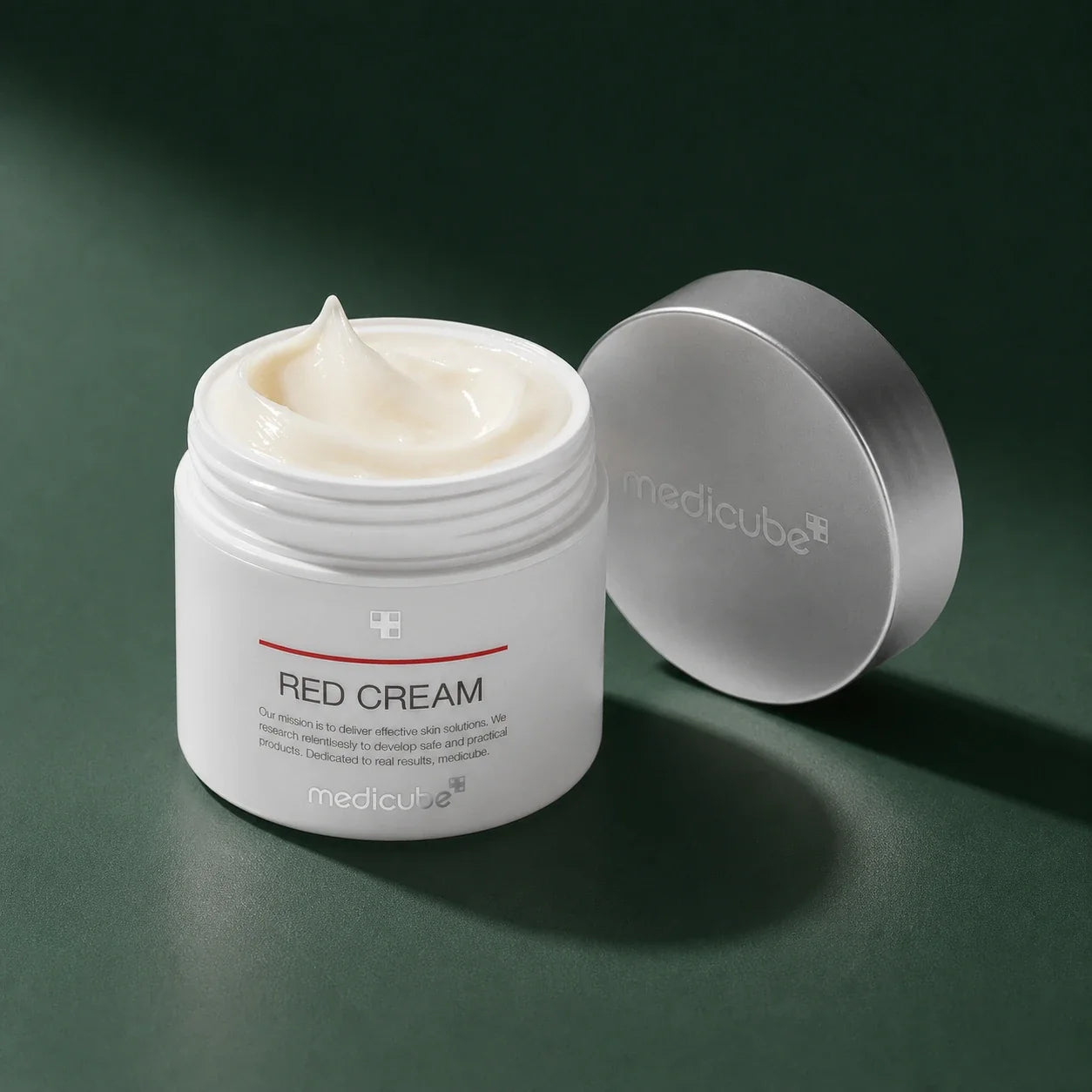 Crème Red 2.0 Plus Medicube ouverte avec texture sur fond vert profond