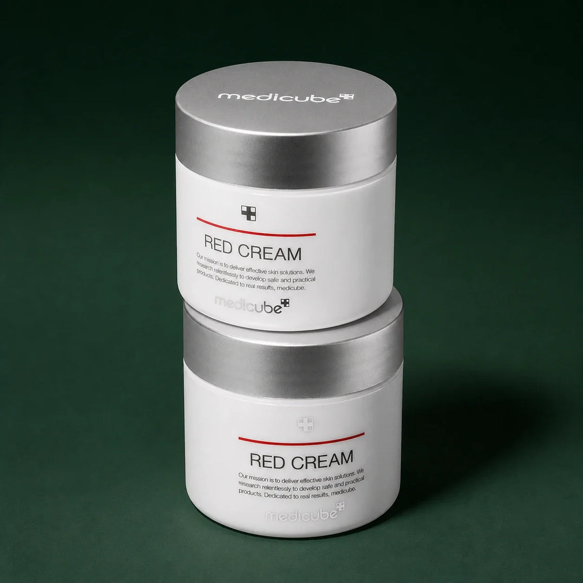 Deux pots de Crème Red 2.0 Plus Medicube sur fond vert profond