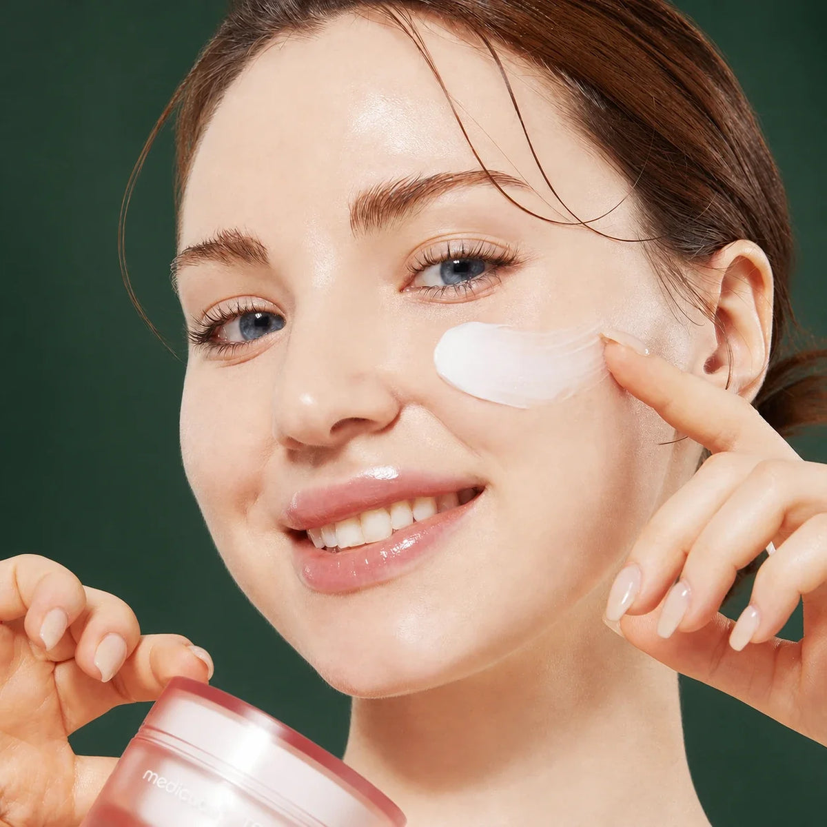 Medicube Crème Triple Collagen 4.0 – application sur la joue sur fond vert premium
