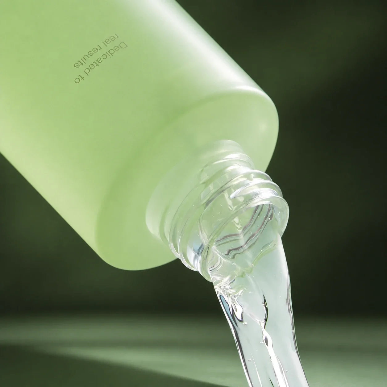 Medicube Lotion Tonique Exosome Cica versée, texture liquide sur fond vert profond