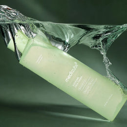 Medicube Lotion Tonique Exosome Cica dans une éclaboussure d’eau sur fond vert profond