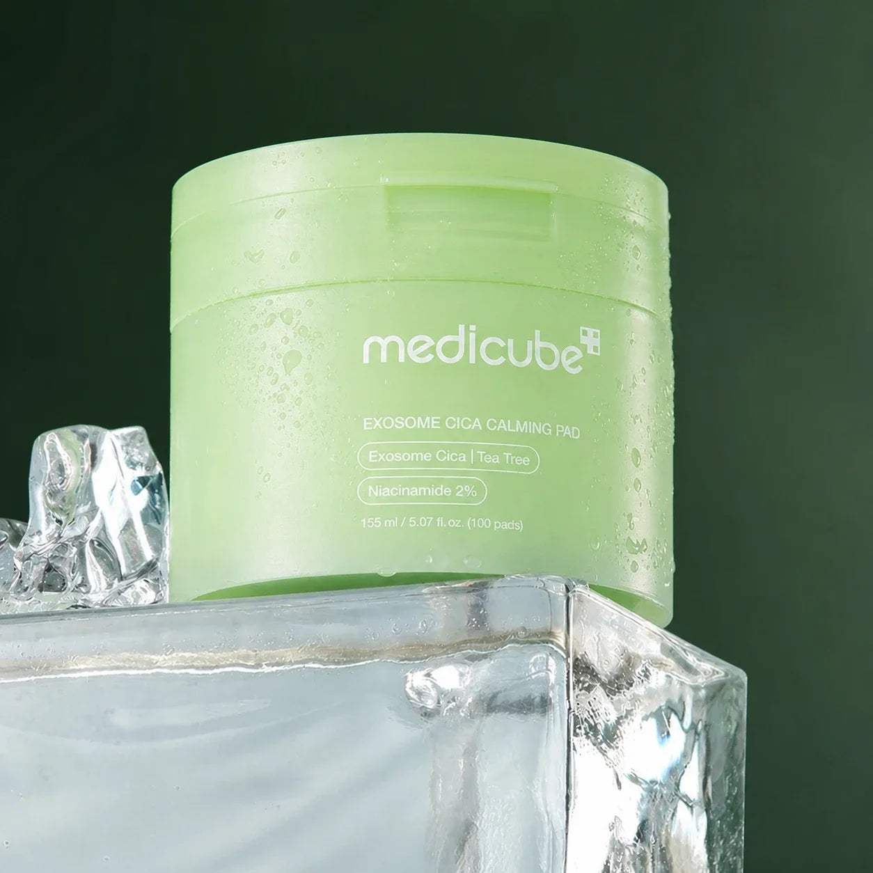 Medicube Pads Apaisants Exosome Cica avec glaçons sur fond vert profond