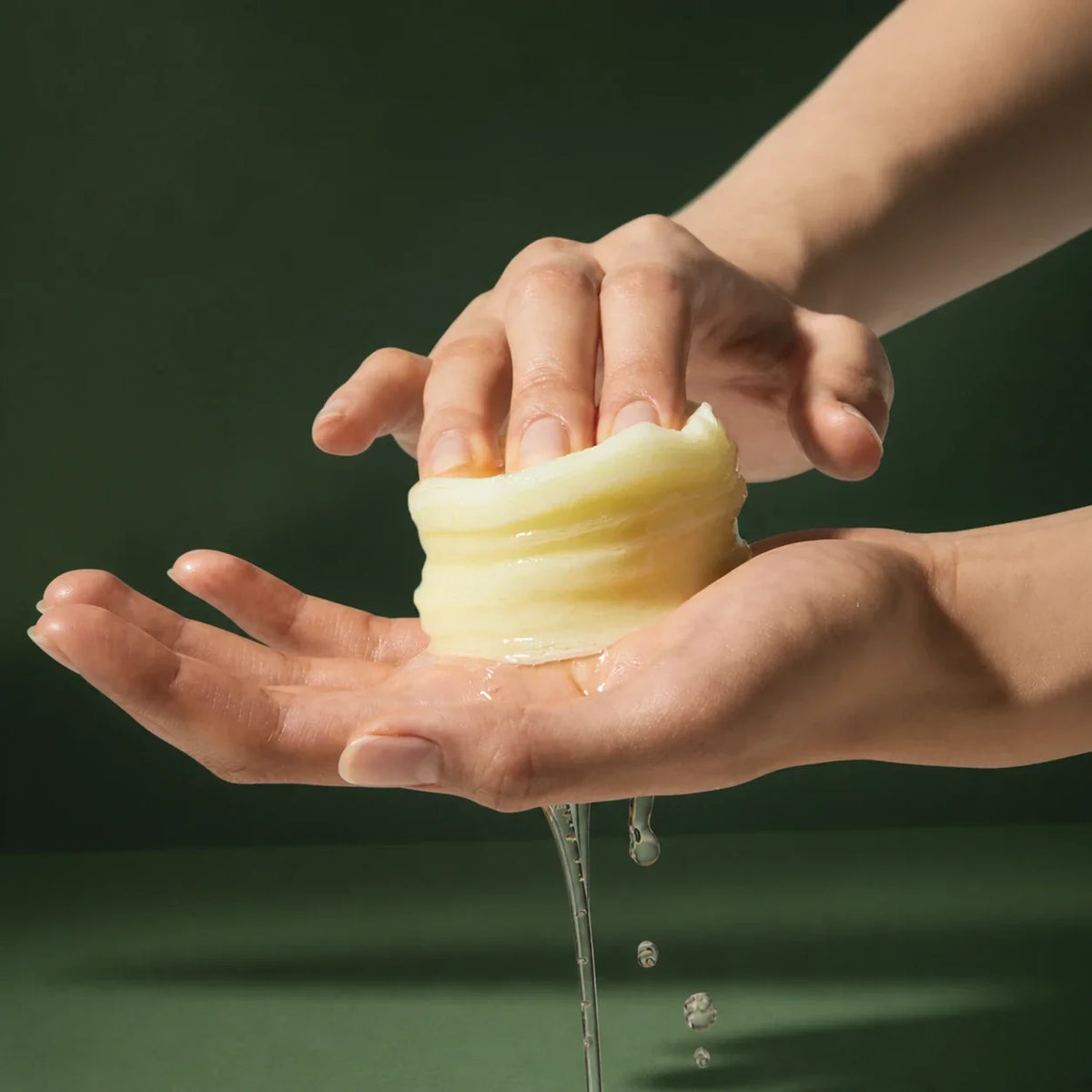 Medicube Pads Éclat Deep Vita C – pad pressé entre les mains sur fond vert premium