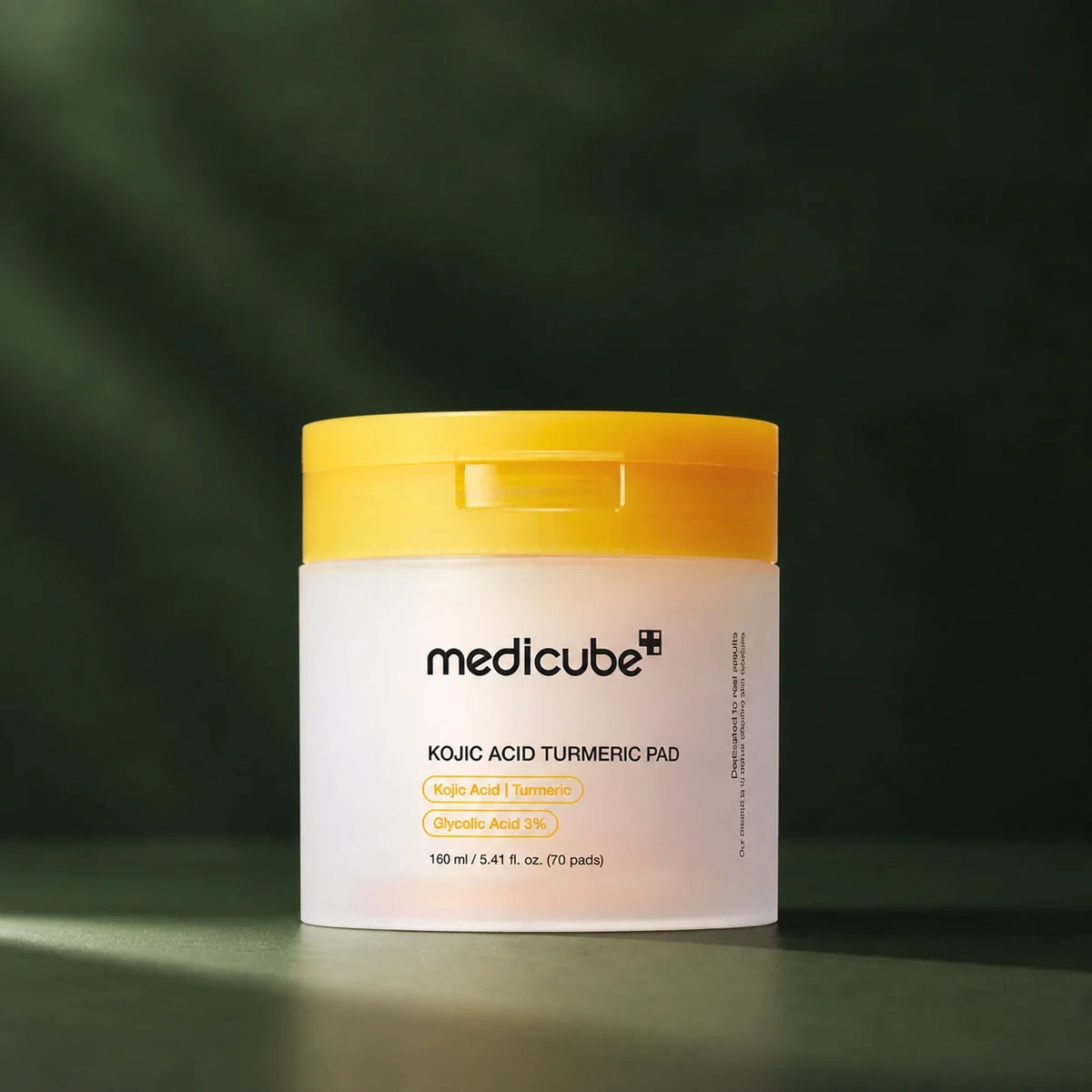 Pads Medicube à l’acide kojique et au curcuma sur fond vert profond