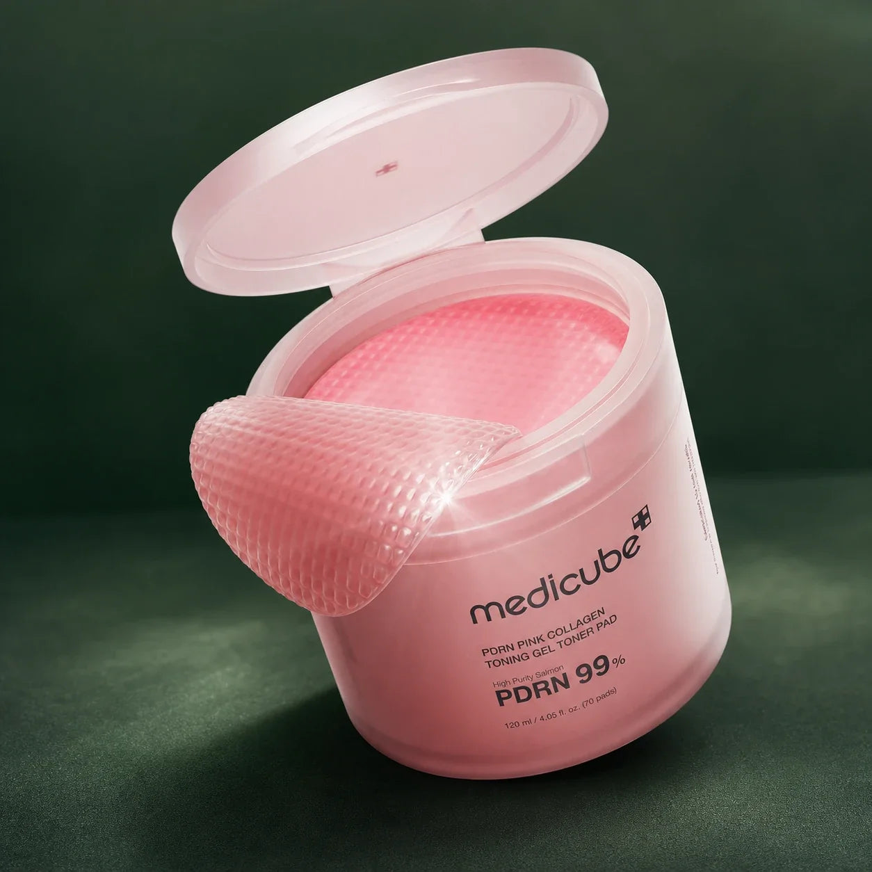 Pot ouvert Medicube PDRN Pink Collagen avec pad sur fond vert profond