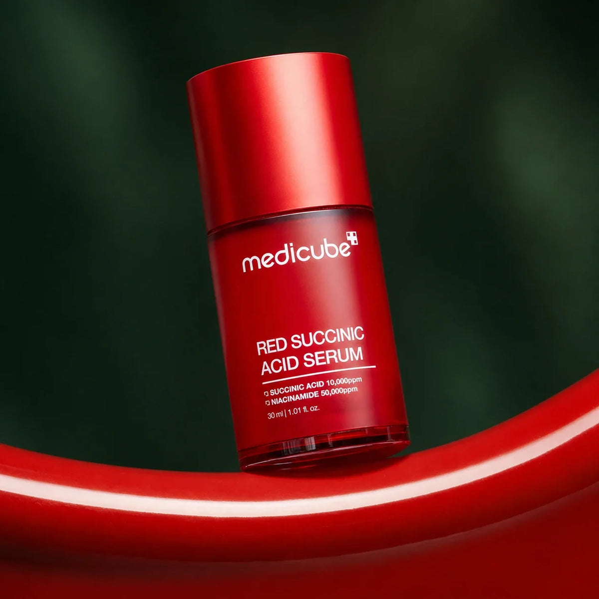 Sérum Red Acide Succinique Medicube sur vague rouge et fond vert profond