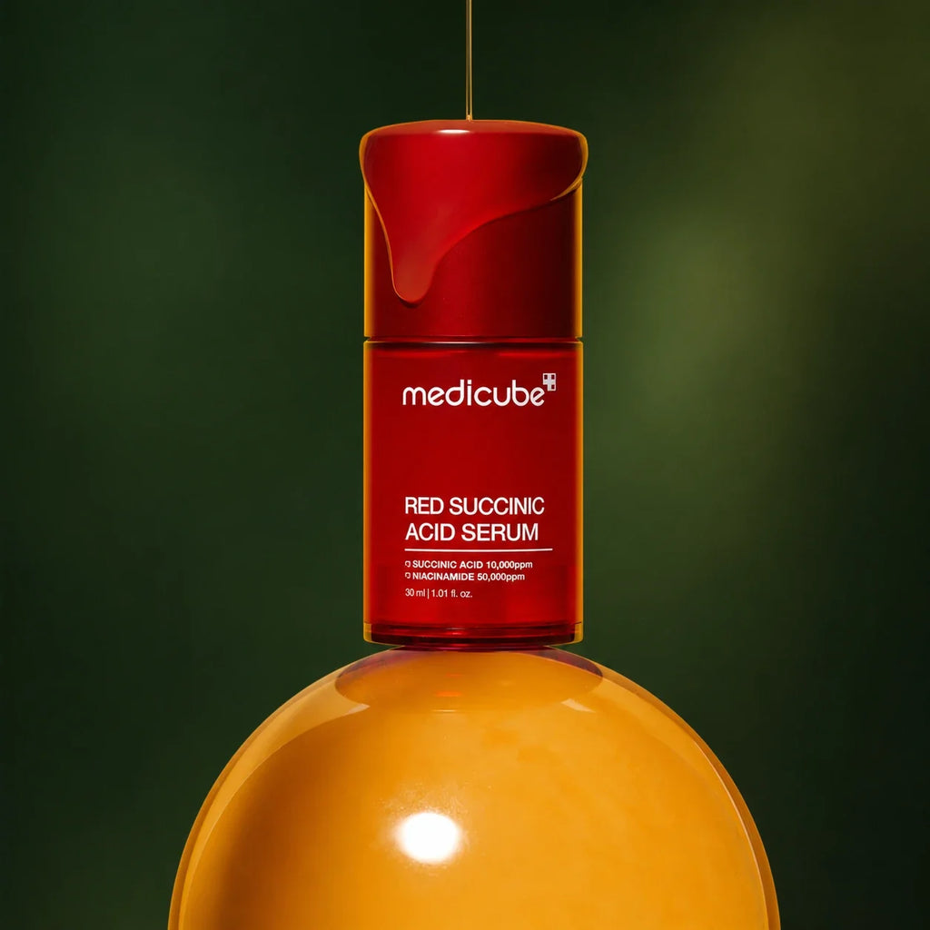 Sérum Red Acide Succinique Medicube avec texture ambrée sur fond vert profond