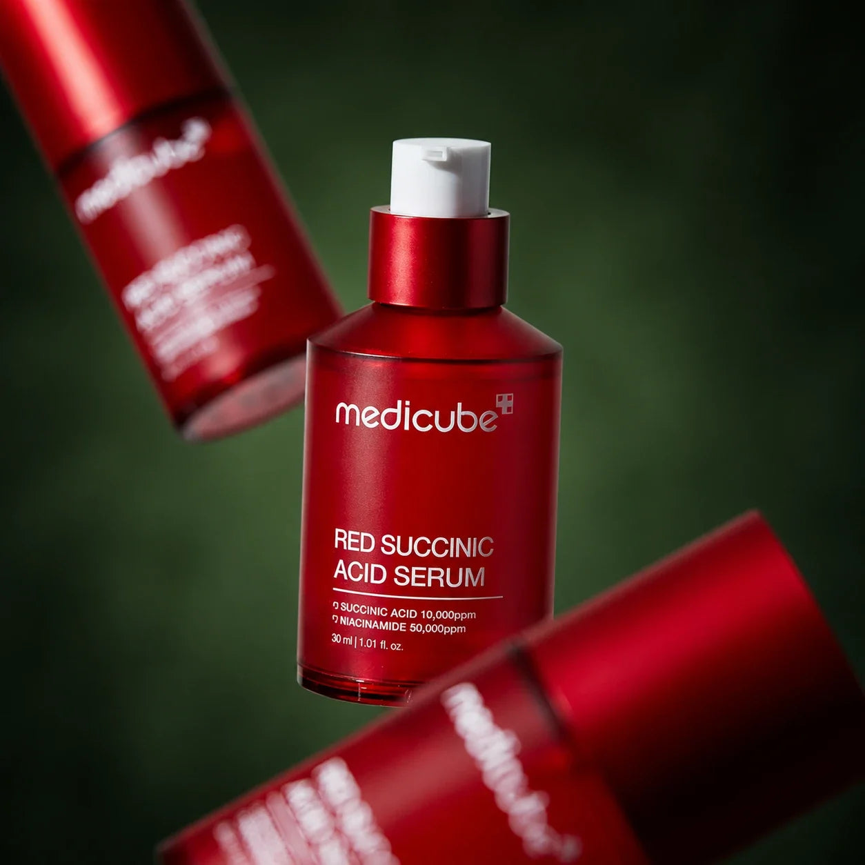 Trois flacons de Sérum Red Acide Succinique Medicube sur fond vert profond