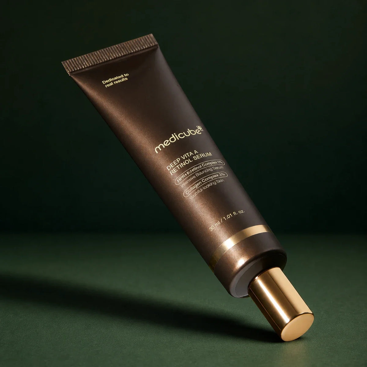 Tube Medicube Deep Vita A Retinol Serum incliné sur fond vert