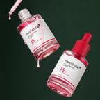 Deux flacons Medicube TXA Niacinamide 15 % sur fond vert profond