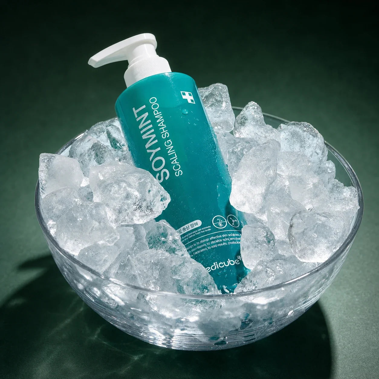 Shampooing Exfoliant Soymint Medicube dans un bol de glace sur fond vert profond
