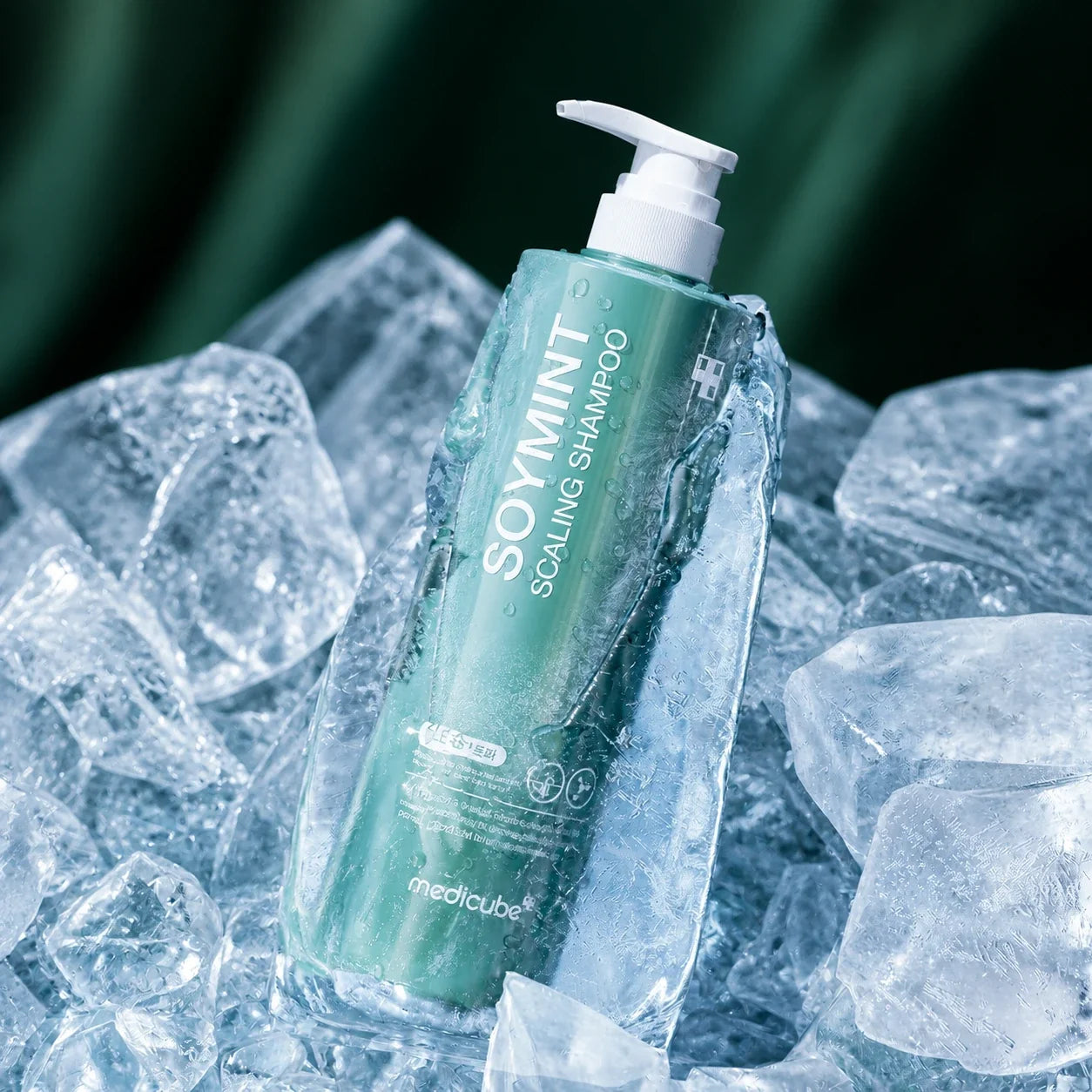 Shampooing Exfoliant Soymint Medicube entouré de glace sur fond vert profond