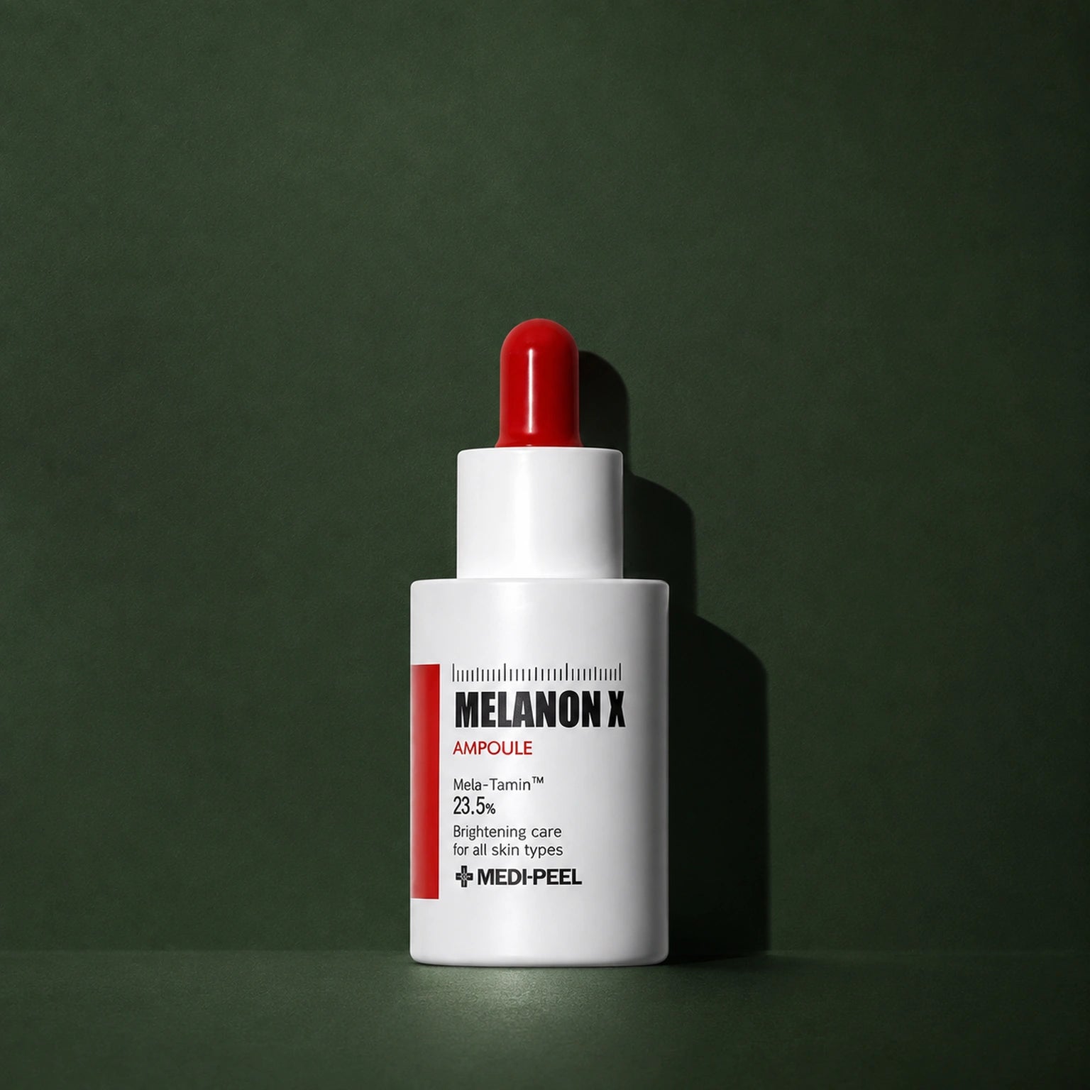 Ampoule Éclat Melanon X MEDIPEEL – vue 2 sur fond vert profond.