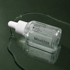 Ampoule Hydratante Hyaluron Layer Mooltox MEDIPEEL – vue 2 sur fond vert profond.