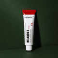 Crème Éclat Melanon X MEDIPEEL – vue principale sur fond vert profond.